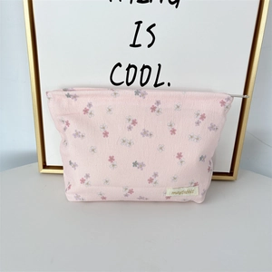 Close-up of pink floral corduroy makeup bag with metal zipper and woven brand label