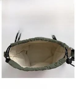 Detail of army green nylon bucket bag with cream lining and woven drawstring cord