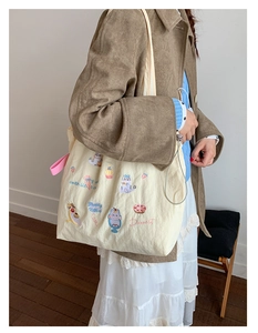 Detail of cream canvas tote bag featuring cute cartoon cat and dessert embroidery