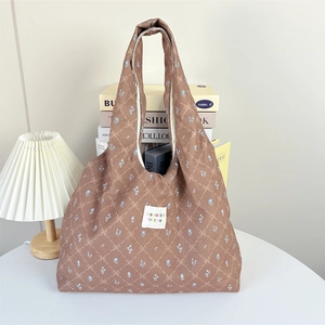 Close-up of brown corduroy tote bag with blue floral patterns and square woven label