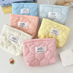 Quilted floral cosmetic bags in pastel colors with embroidered label on white background