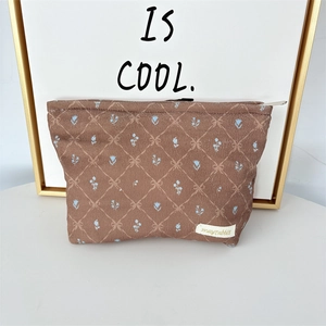 Close-up of corduroy bow makeup bag with floral patterns and smooth metal zipper detail