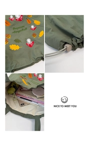 Close-up of mushroom and maple leaf embroidery on forest green nylon tote bag