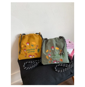 Close-up of forest theme embroidery with mushrooms and acorns on nylon drawstring bags