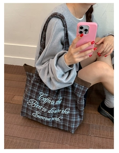 Detail of plaid canvas tote bag with brown corduroy trim and white coffee quote embroidery