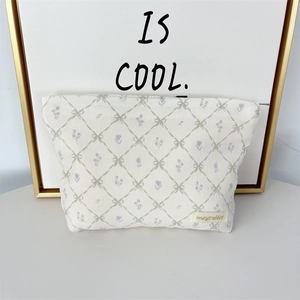 Detail of corduroy makeup bag with green bow patterns and brand woven label