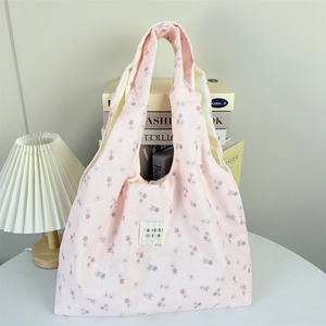 Detailed texture of pink corduroy tote bag with floral print and central fabric brand label