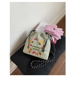Detail of light green nylon crossbody bag with colorful floral embroidery and rope strap
