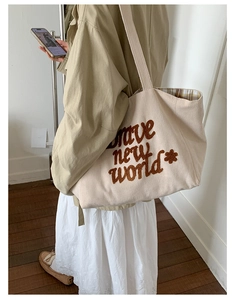Detail of corduroy tote bag with brave new world embroidery and plaid lining