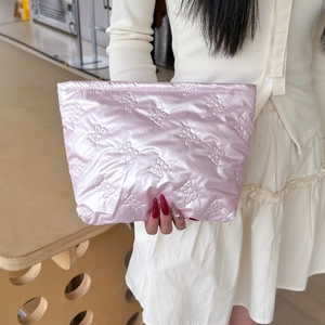 Close-up of light pink satin quilted bag with embroidered bow patterns and smooth texture