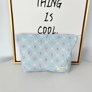 Detail of light blue corduroy makeup bag with quilted floral pattern and metal zipper