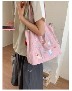 Close-up of pink canvas tote bag featuring cute cat and cupcake embroidery and drawstring