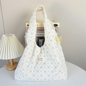 Detail of corduroy tote bag featuring floral diamond pattern and woven brand label