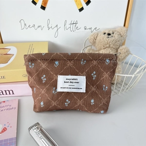 Détail d'une trousse à maquillage en velours marron avec motifs de nœuds et fleurs douces