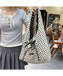 Detailed view of canvas tote bag featuring large black polka dots and side bow detail