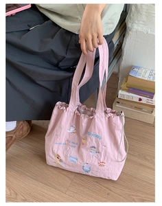 Close-up of pink drawstring tote bag featuring detailed cute cat and cupcake embroidery