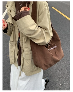 Detail of dark brown corduroy tote bag featuring white text print and drawstring closure