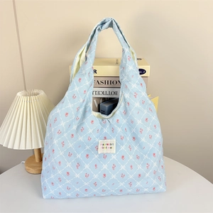 Detail of light blue floral corduroy tote bag showing textured fabric and brand label