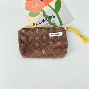 Close-up of brown corduroy coin purse with floral embroidery and yellow zipper handle