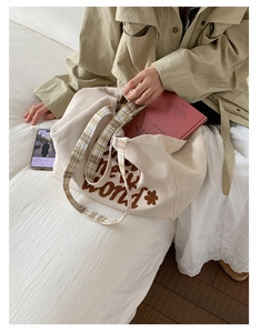 Detail of beige corduroy tote bag with embroidery and checkered shoulder strap