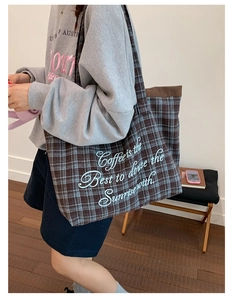 Detail of checkered tote bag with corduroy trim and printed slogan for daily commute