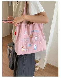 Detailed embroidery of cat and cupcakes on pink drawstring nylon tote bag