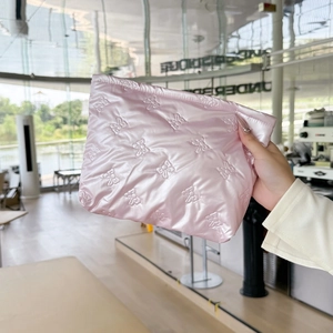 Detailed texture of pink satin quilted makeup bag with embossed bow patterns and stitching