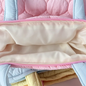 Detail of quilted nylon tote bag showing interior lining and smooth resin zipper closure