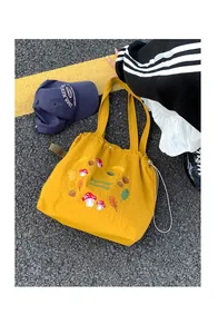 Detail of mushroom embroidery on a yellow canvas tote bag with drawstring closure
