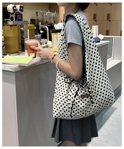 Detailed view of polka dot canvas tote bag shown in a casual lifestyle cafe setting
