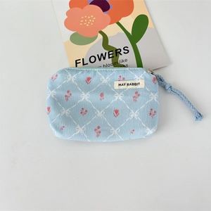 Close-up of blue floral corduroy coin purse with diamond pattern and May Rabbit label