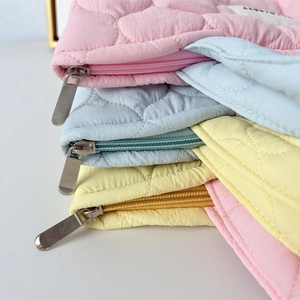Macro detail of quilted puffer texture and zipper on candy-colored mummy storage bags