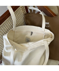 Detail of the internal zipper pocket and durable canvas texture on a large tote bag
