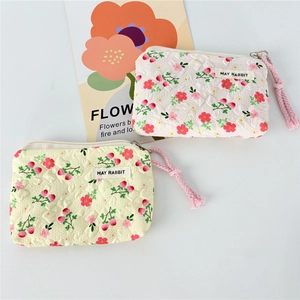 Macro view of quilted canvas coin purses with floral prints and woven MAY RABBIT brand label