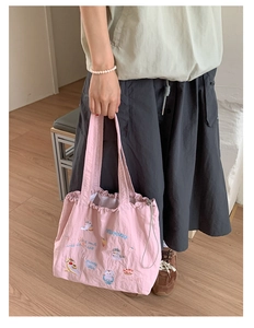 Detailed embroidery of cat and cupcake on a pink drawstring tote bag with long handles
