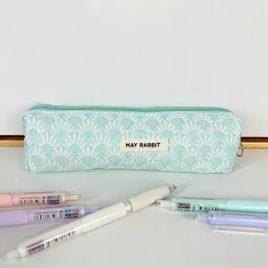 Detalle del estuche jacquard verde menta con bordado festoneado y etiqueta de tela
