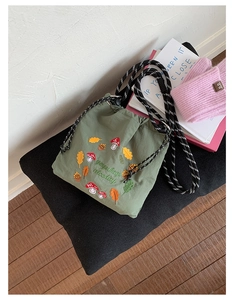 Detail of green nylon bag showing forest embroidery and adjustable thick rope strap