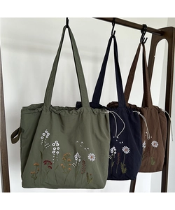 Detailed view of floral embroidery on canvas tote bags in green, navy and brown