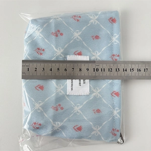 Vue détaillée d'une pochette en velours bleu fleuri avec règle mesurant 14cm de large