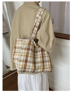 Detailed back view of a vintage plaid canvas tote bag worn on shoulder for daily use