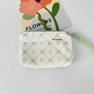 Detail of floral corduroy coin purse featuring green plaid pattern and woven wristlet strap