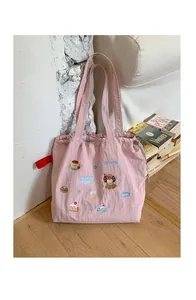 Pink drawstring tote bag featuring cute cartoon embroidery on soft fabric surface