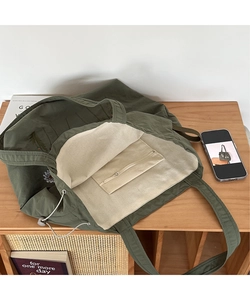 Detailed internal view of dark green tote bag with white dandelion embroidery and drawstring closure
