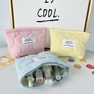 Detailed view of quilted makeup bags in pink, yellow, and blue with heart patterns