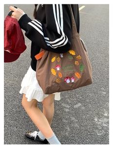 Detailed embroidery of colorful mushrooms and leaves on a large brown nylon tote bag