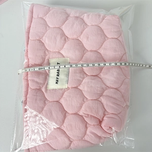Pink quilted handbag detail with brand label and ruler measurement showing 24cm width