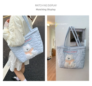 Detail showing light blue heart-quilted tote bag with cute plush puppy patch and lucky embroidery