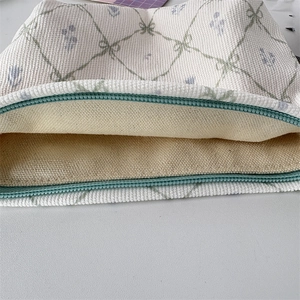 Détail de la fermeture éclair vert menthe et du motif floral sur la trousse en velours