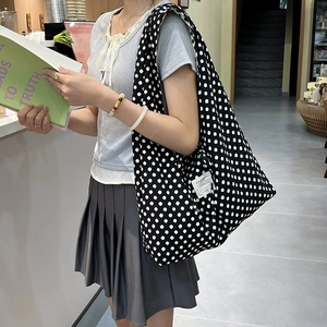 Polka dot canvas tote bag in black and white shown as a crossbody bag for daily use