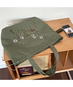 Detail of olive green canvas tote bag featuring floral embroidery and side drawstring